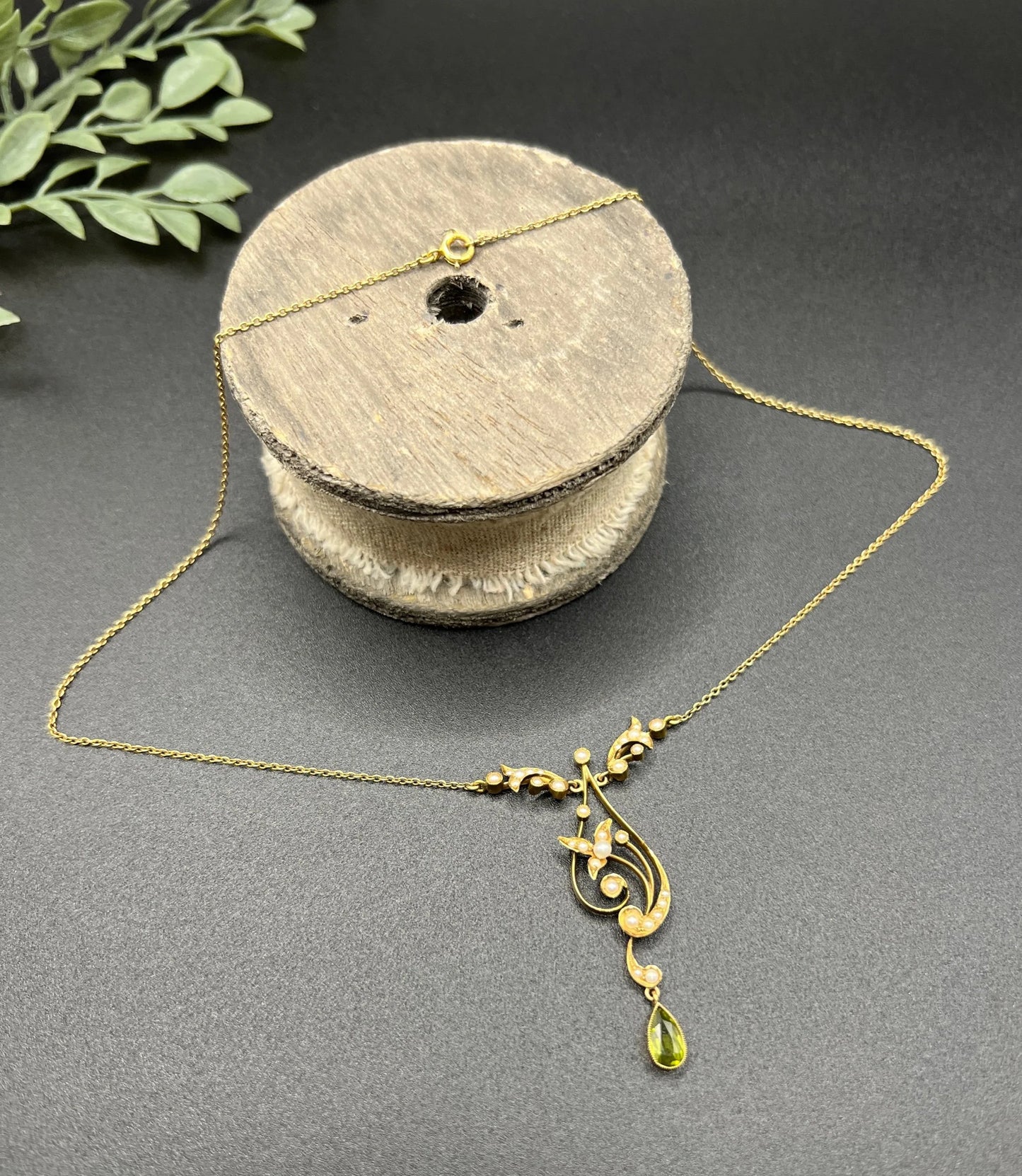 A yellow gold floral pendant necklace with pearls and a peridot drop