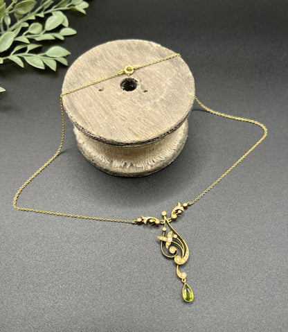 A yellow gold floral pendant necklace with pearls and a peridot drop