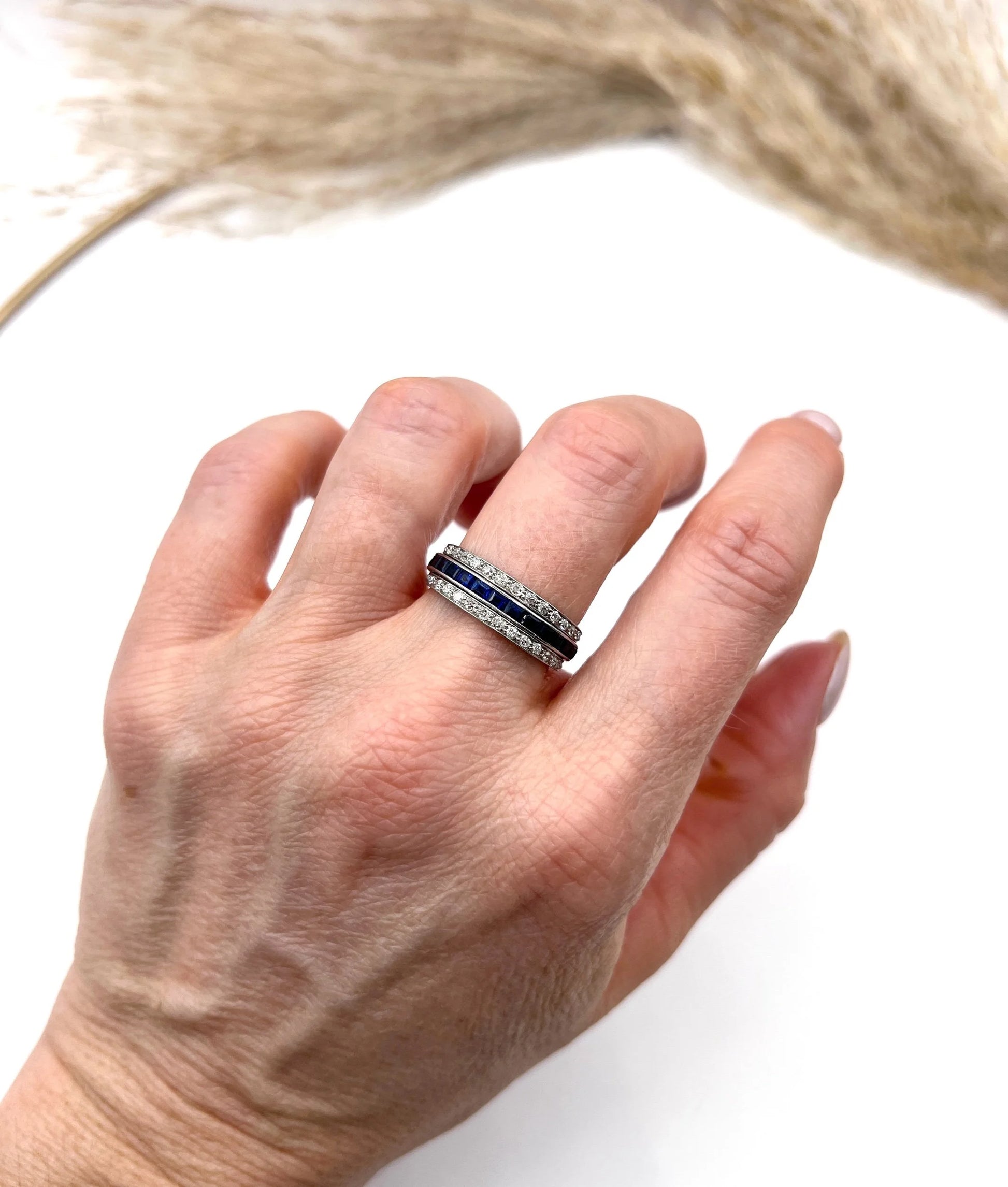 A platinum night and day flip band ring set with diamonds, sapphires and rubies, modelled on a hand