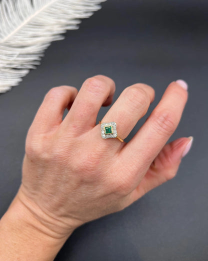 An emerald and diamond cluster ring in yellow gold and platinum, modelled on a hand