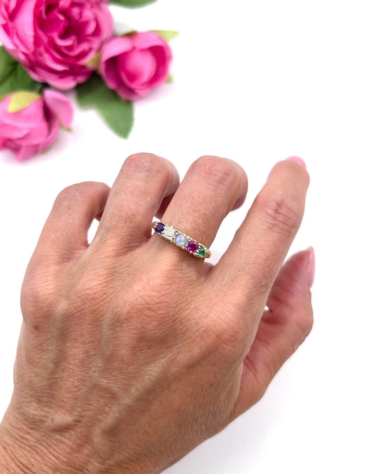 A five stone acrostic ring in yellow gold with amethyst, diamond, opal, ruby and emerald, modelled on a hand