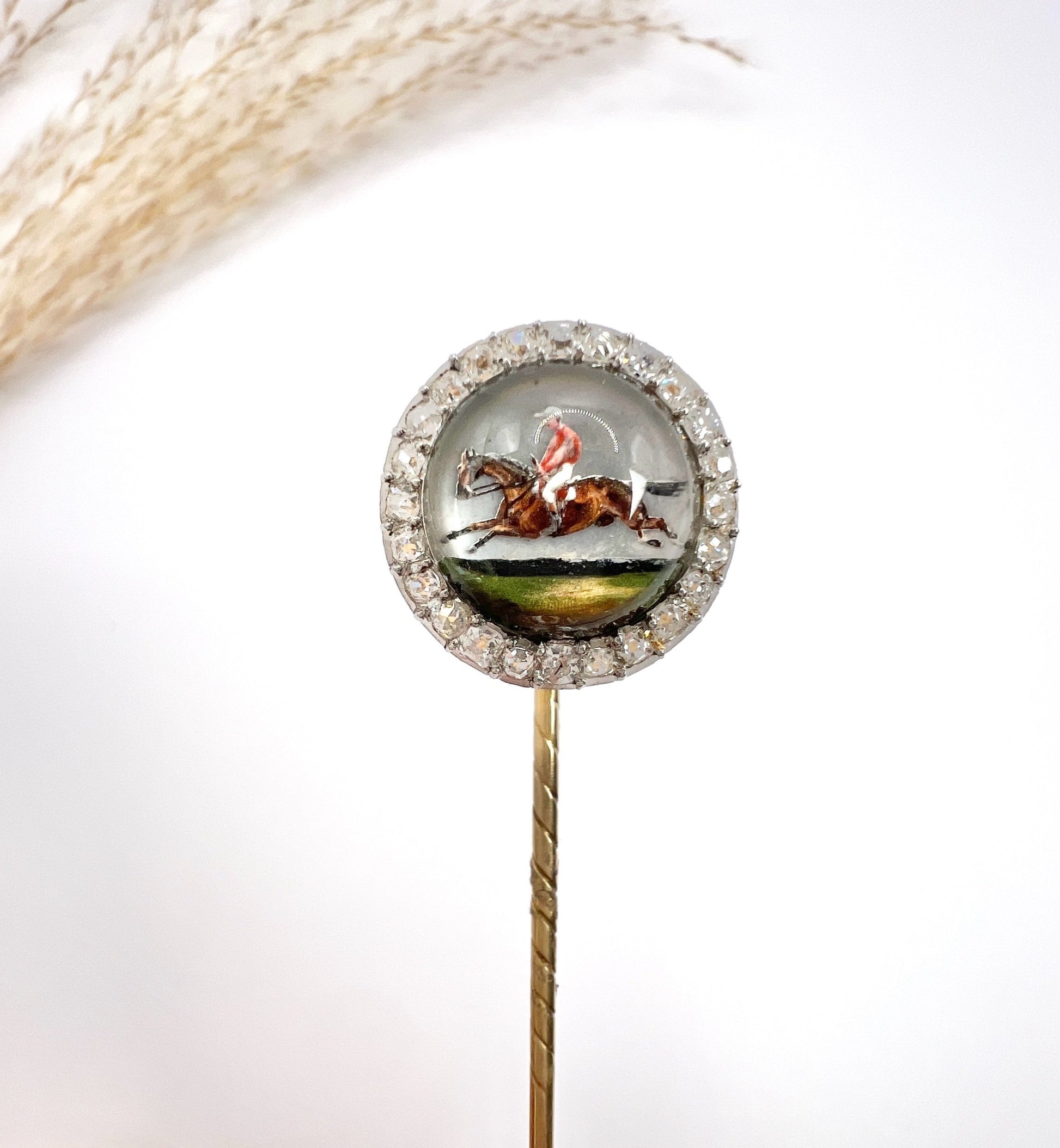An antique Essex glass and diamond stick pin depicting a jockey riding a horse