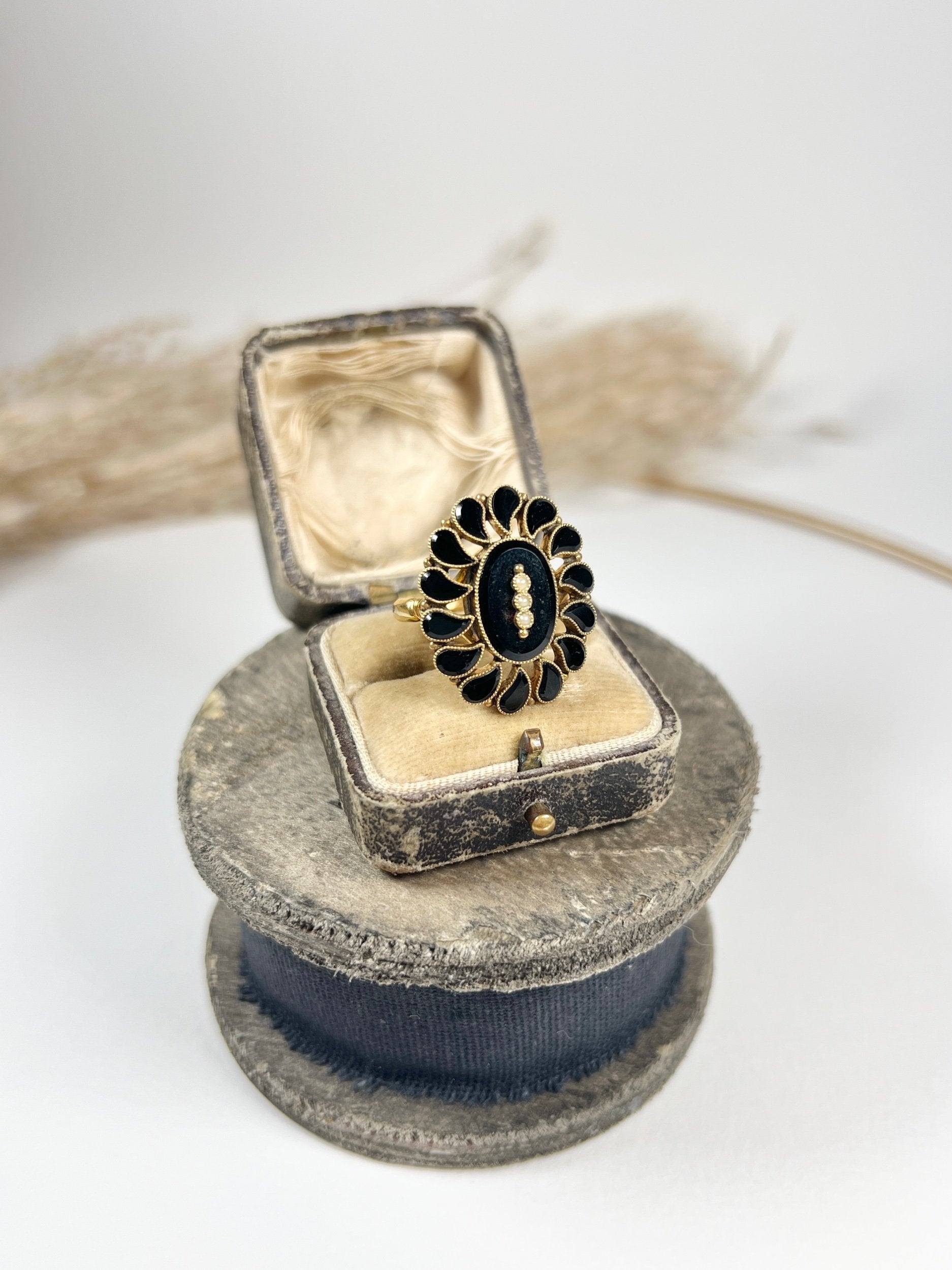 A black onyx and seed pearl fancy halo cluster ring in yellow gold, in a ring box