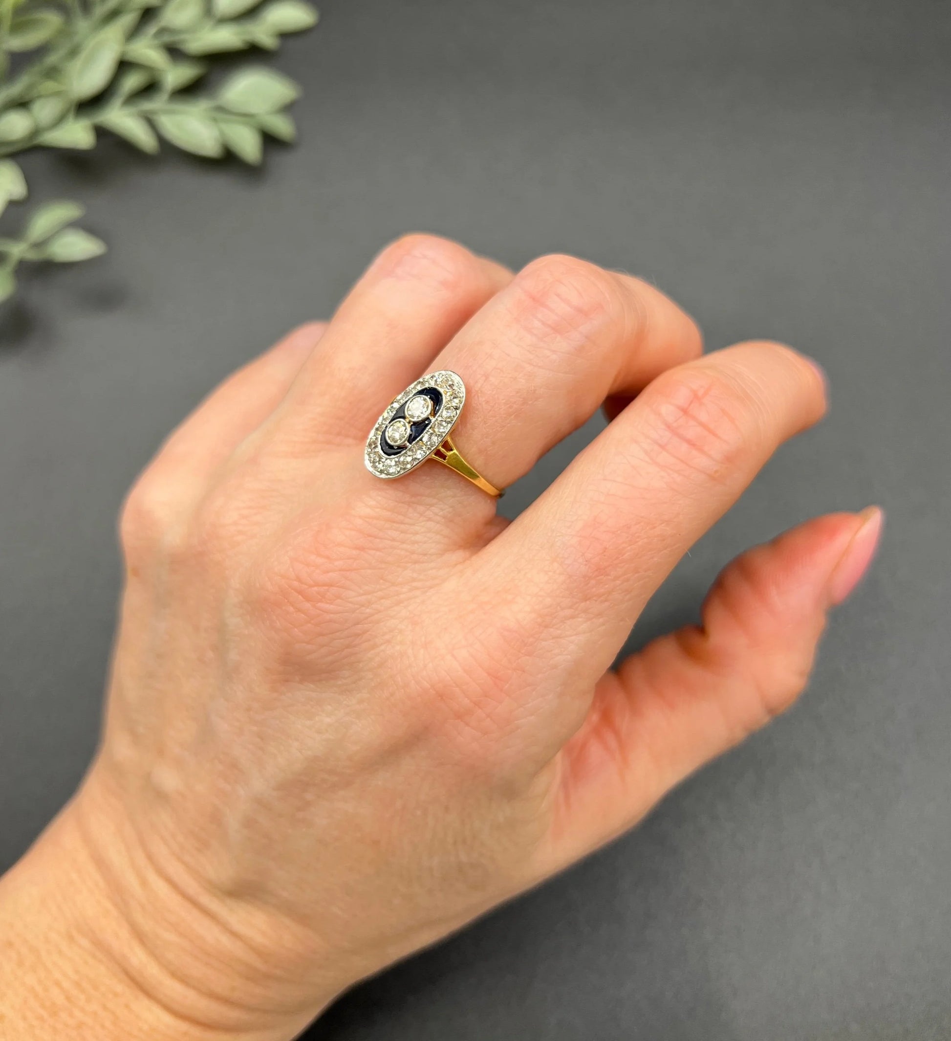 An oval cluster ring with diamonds and sapphires in platinum and yellow gold, modelled on a hand