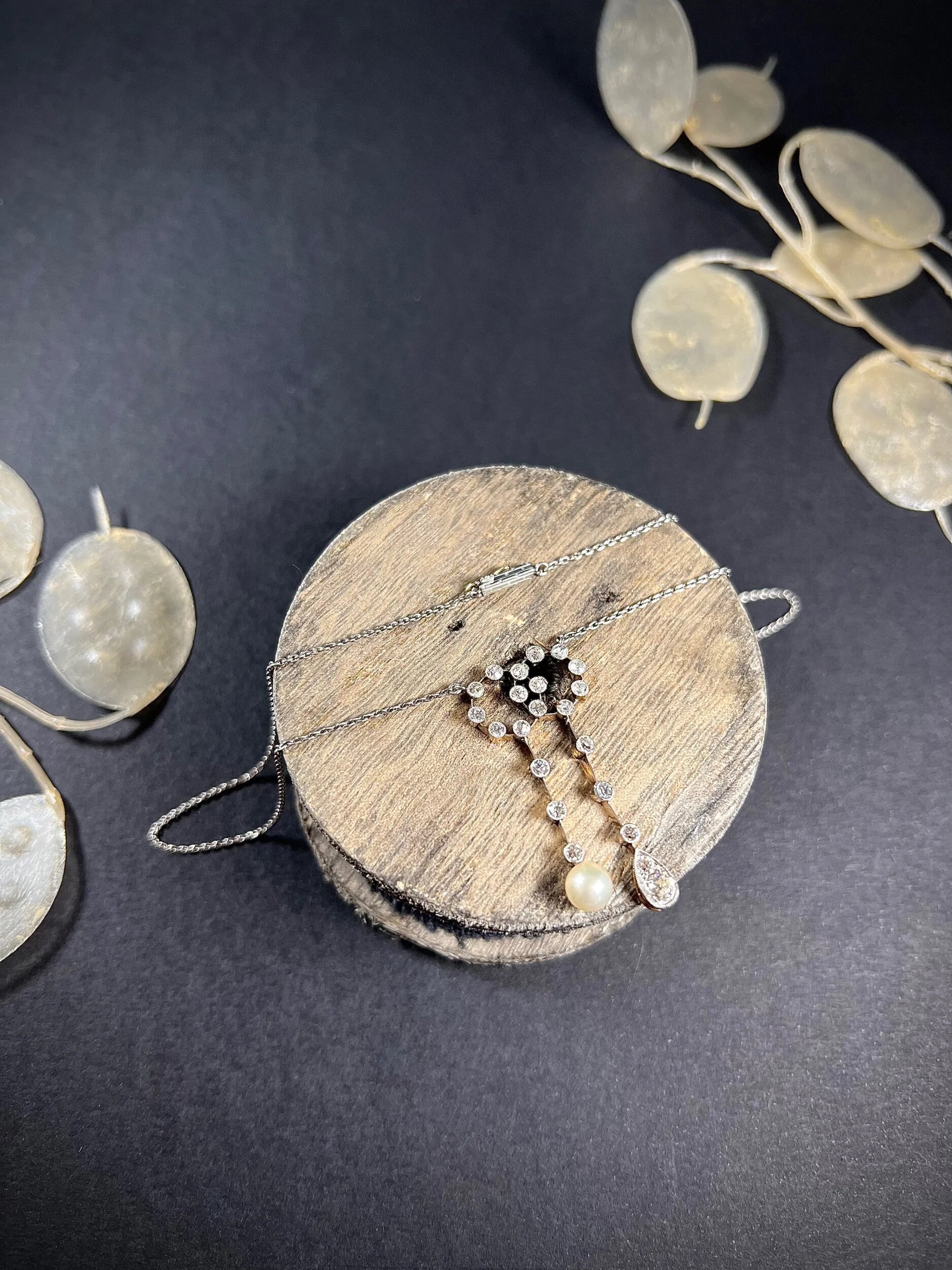 An antique diamond and pearl double drop pendant necklace, on a wooden spool