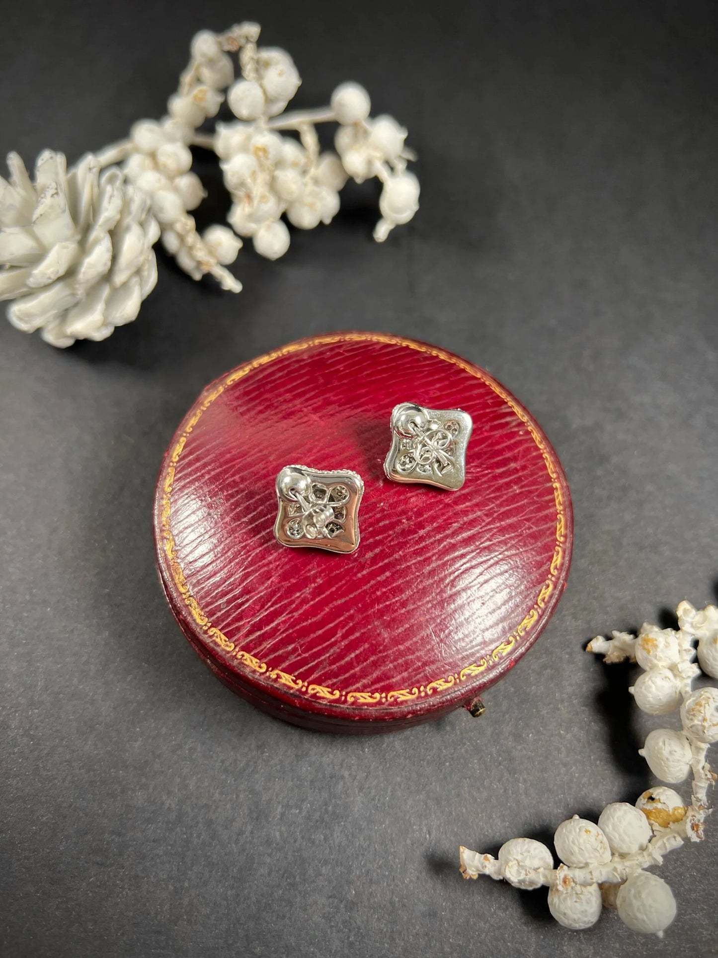 A pair of diamond cluster stud earrings in white gold, on an antique box