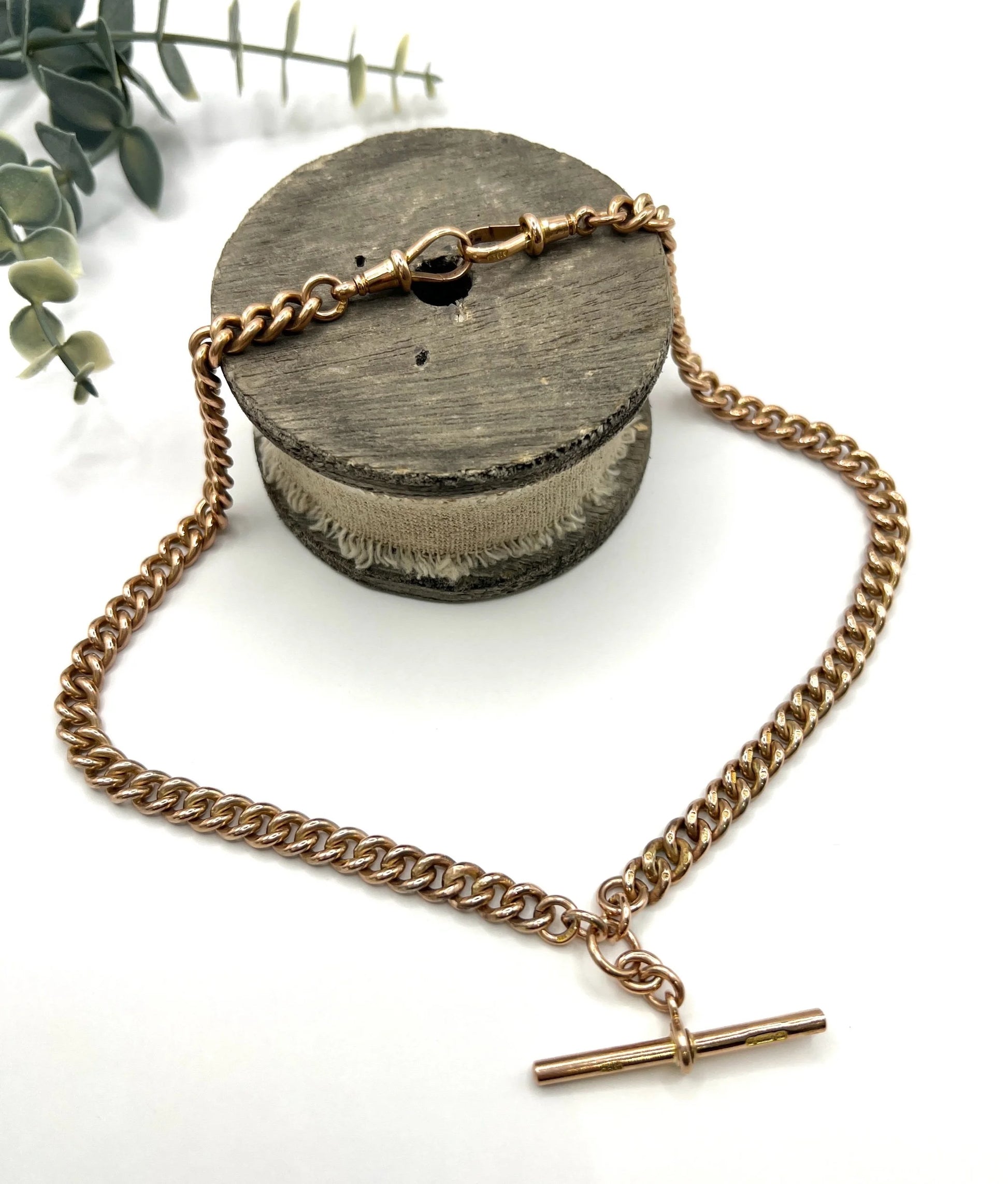 A rose gold curb link Albert chain on a white background