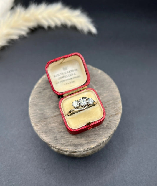 A three stone diamond crossover ring, in a red antique ring box