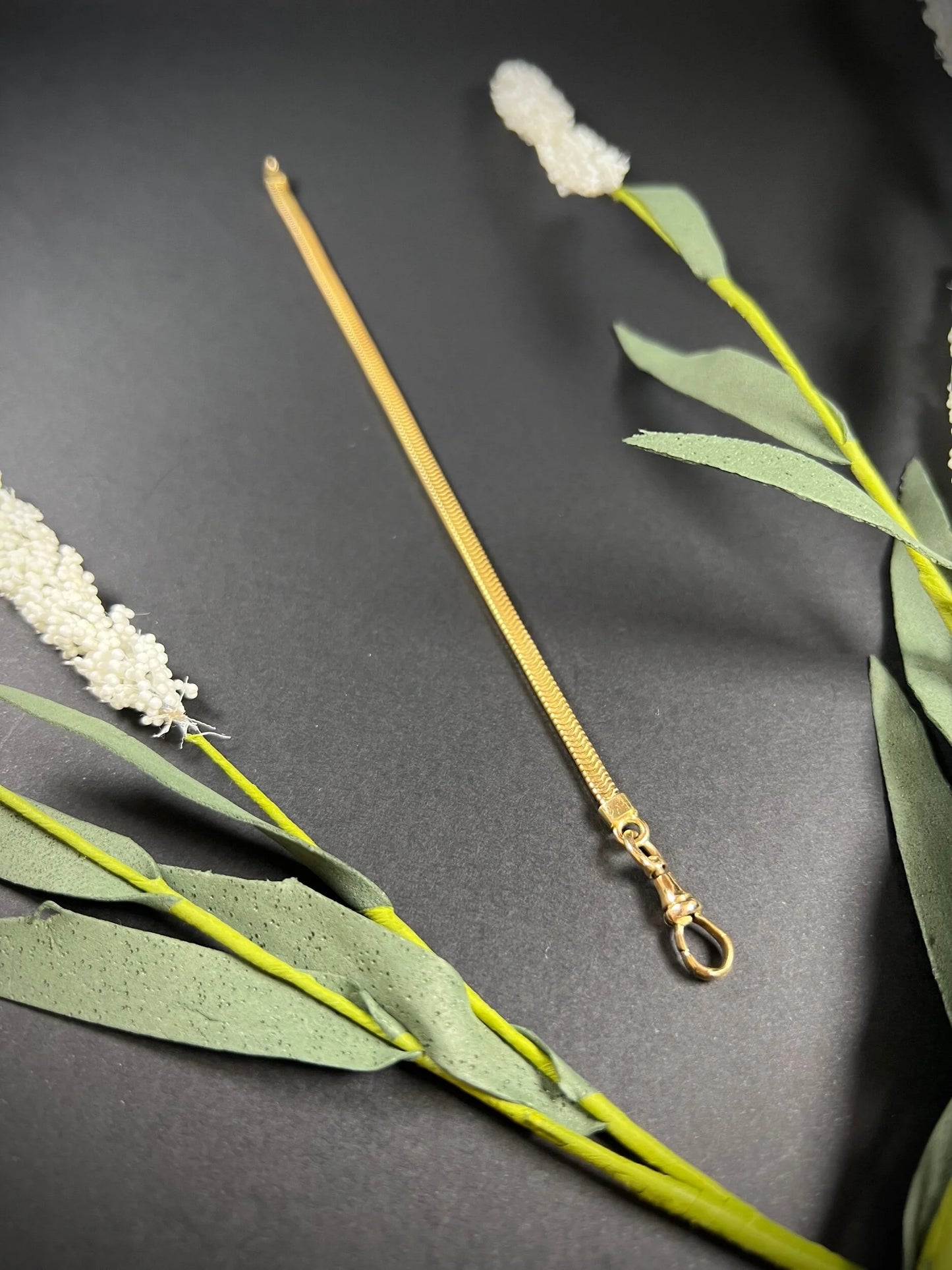 A yellow gold snake link bracelet, laid flat on a black background