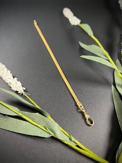 A yellow gold snake link bracelet, laid flat on a black background