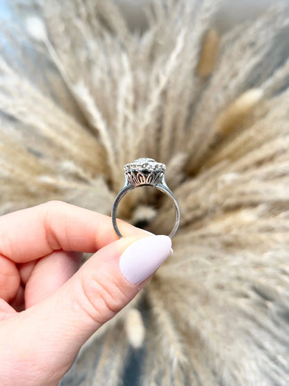 A navette shaped diamond cluster ring in white metal, held in a hand
