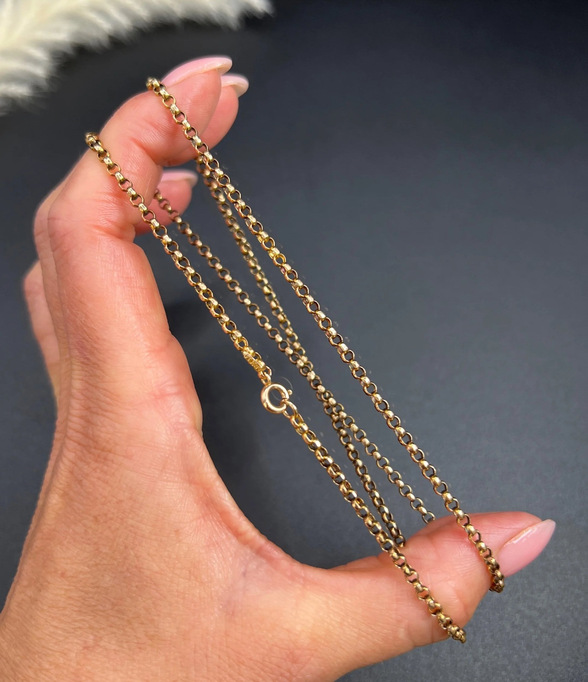A gold belcher link necklace, held in a hand