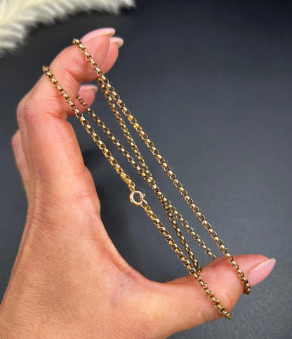 A gold belcher link necklace, held in a hand