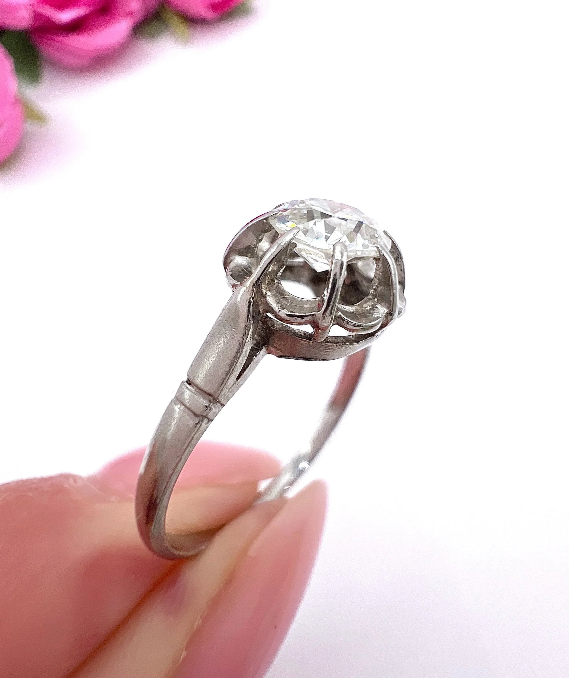 A solitaire diamond ring in platinum, held in a hand