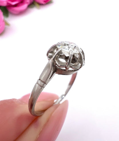 A solitaire diamond ring in platinum, held in a hand