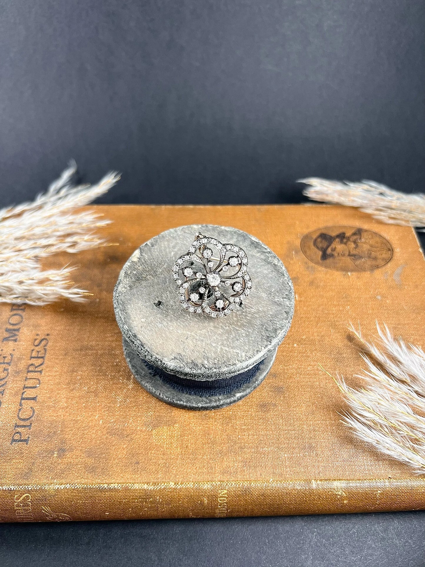 A floral design diamond set pendant/brooch, on an antique box