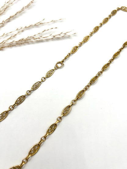 A yellow gold fancy link chain on a white background