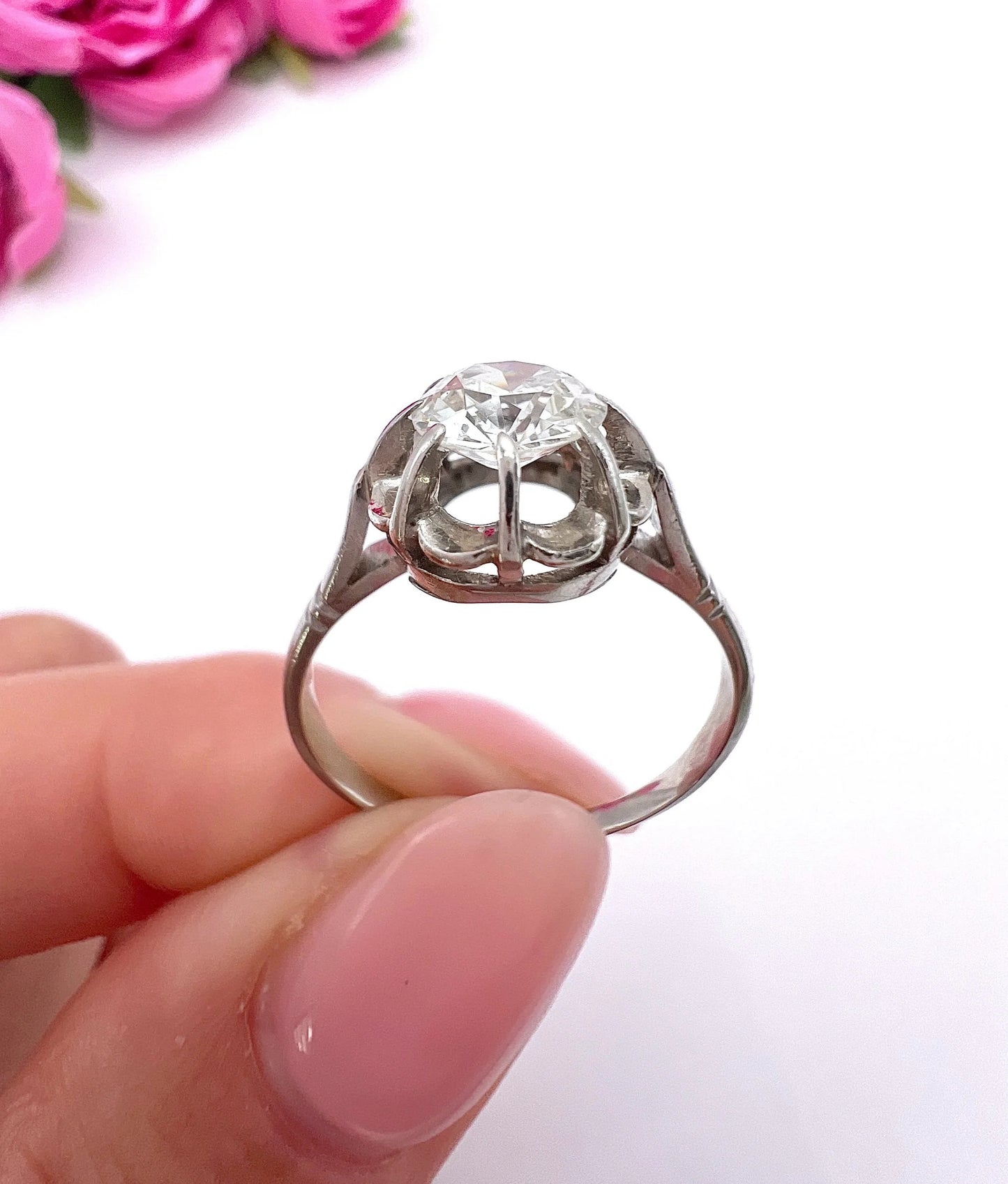 A solitaire diamond ring in platinum, held in a hand