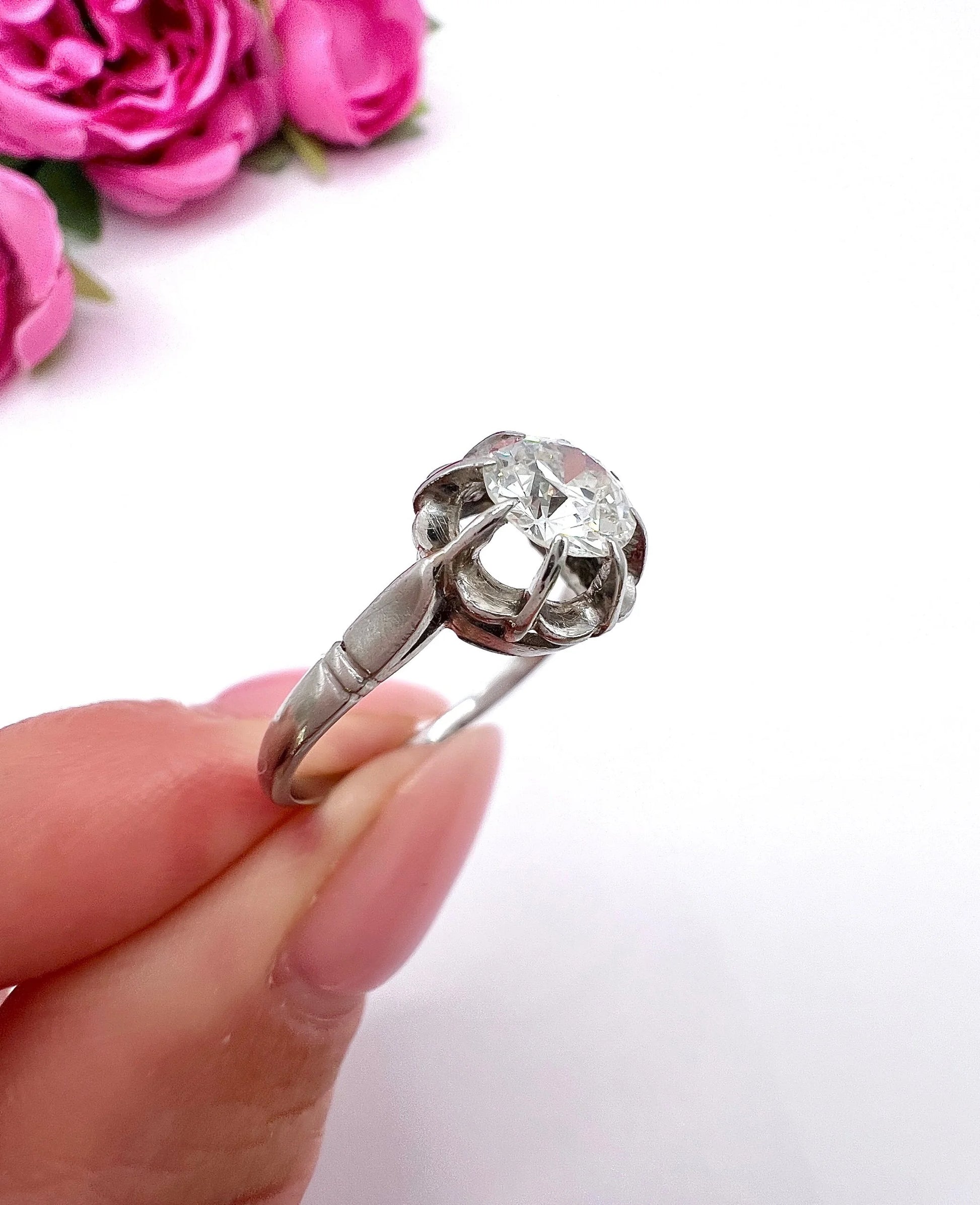 A solitaire diamond ring in platinum, held in a hand
