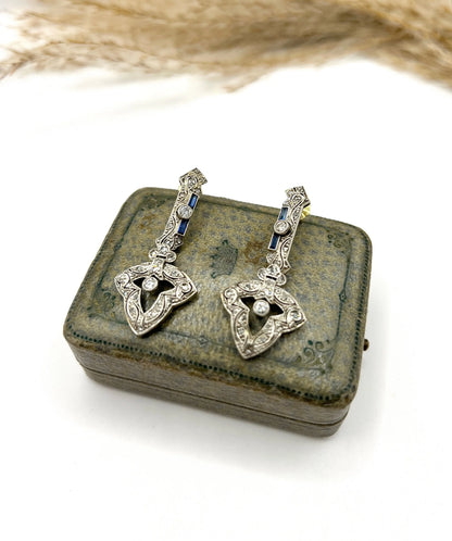 A pair of diamond and sapphire drop earrings, on an antique box