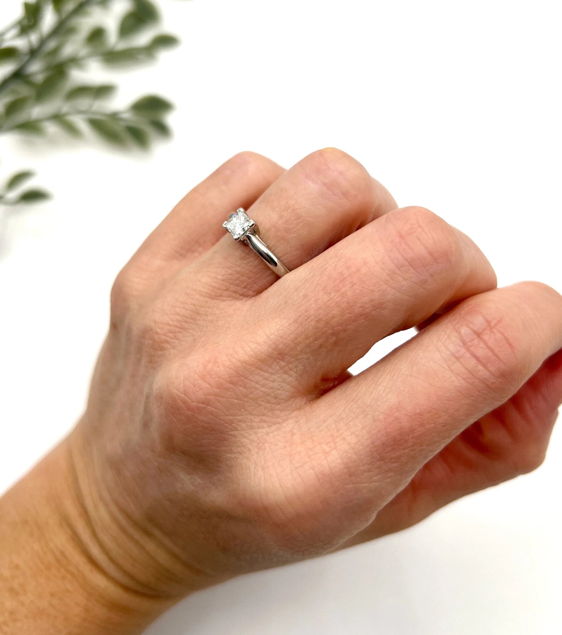 A princess cut diamond solitaire ring in platinum, modelled on a hand
