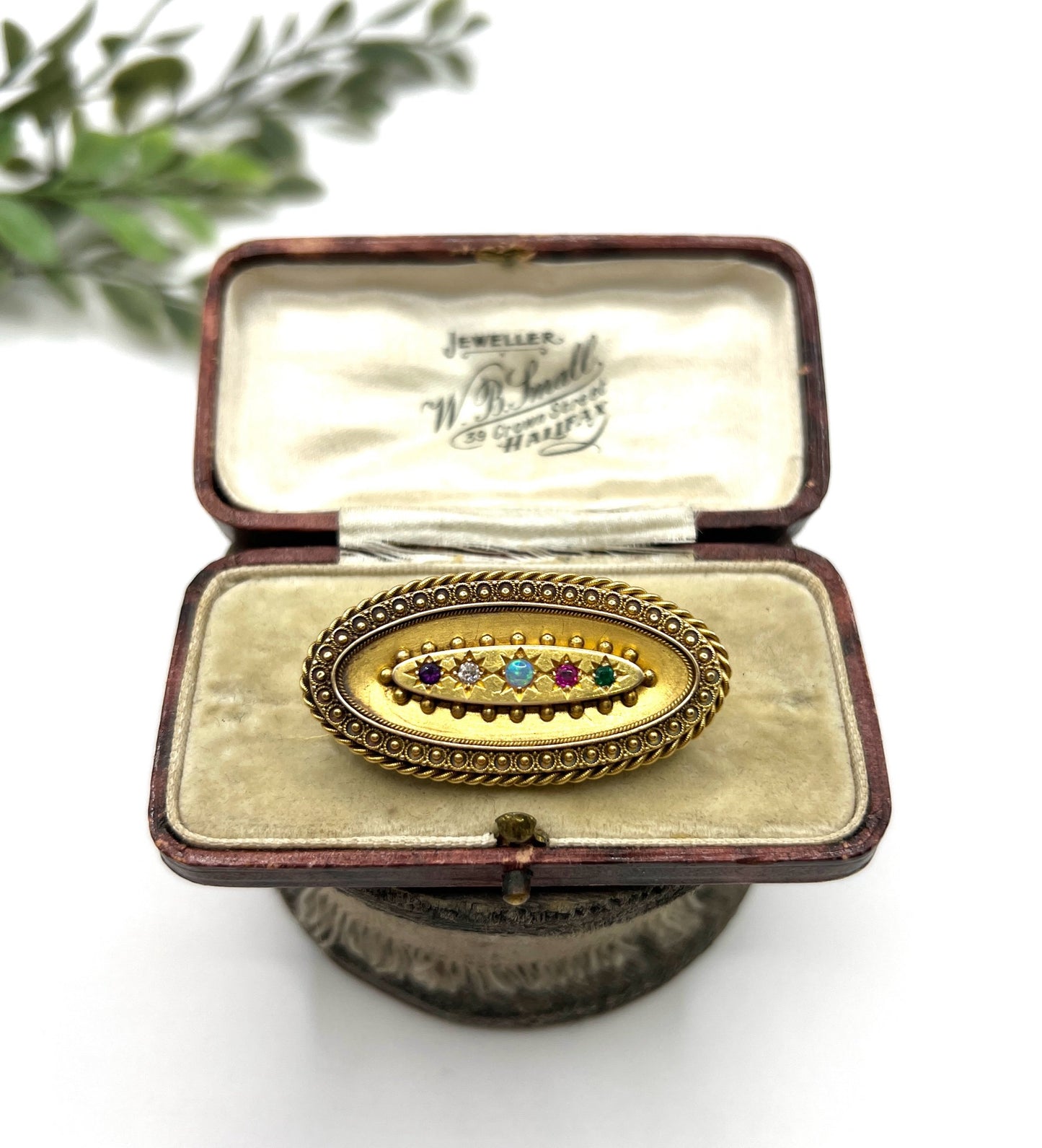 An oval yellow gold multi-gemstone acrostic brooch, in an antique box