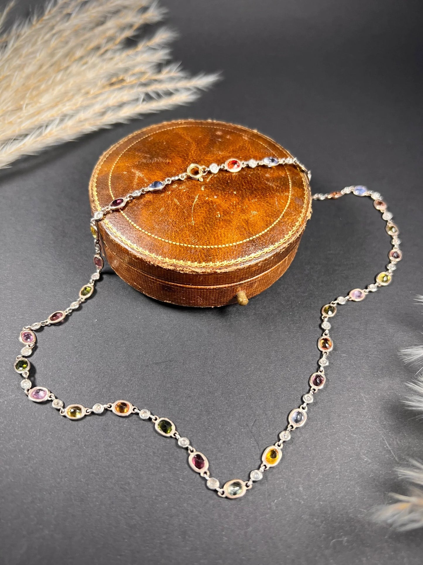 A coloured sapphire and diamond set necklace in platinum and gold, on an antique box