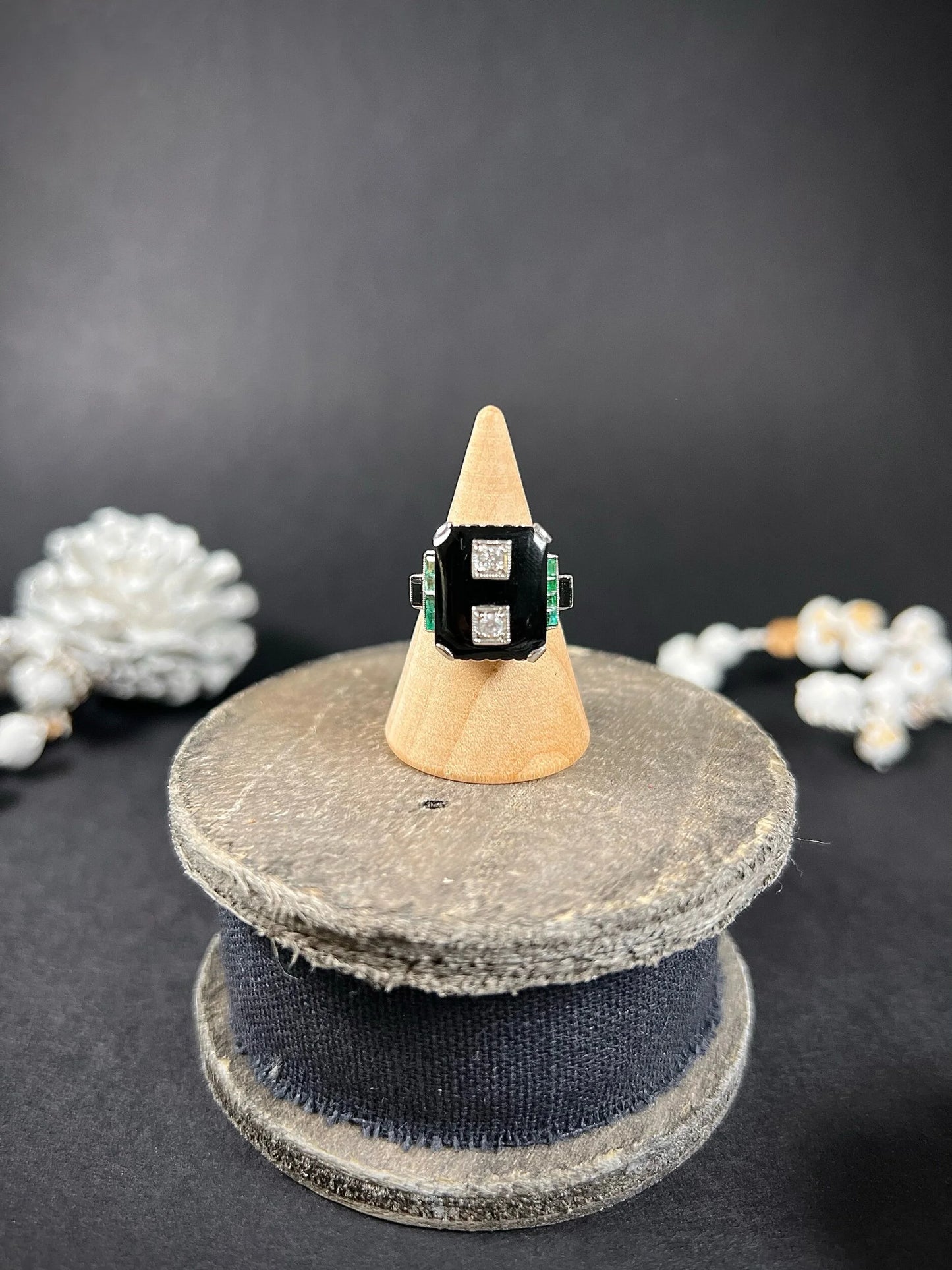 A geometric black onyx ring with diamonds and emeralds in white gold, on a ring cone