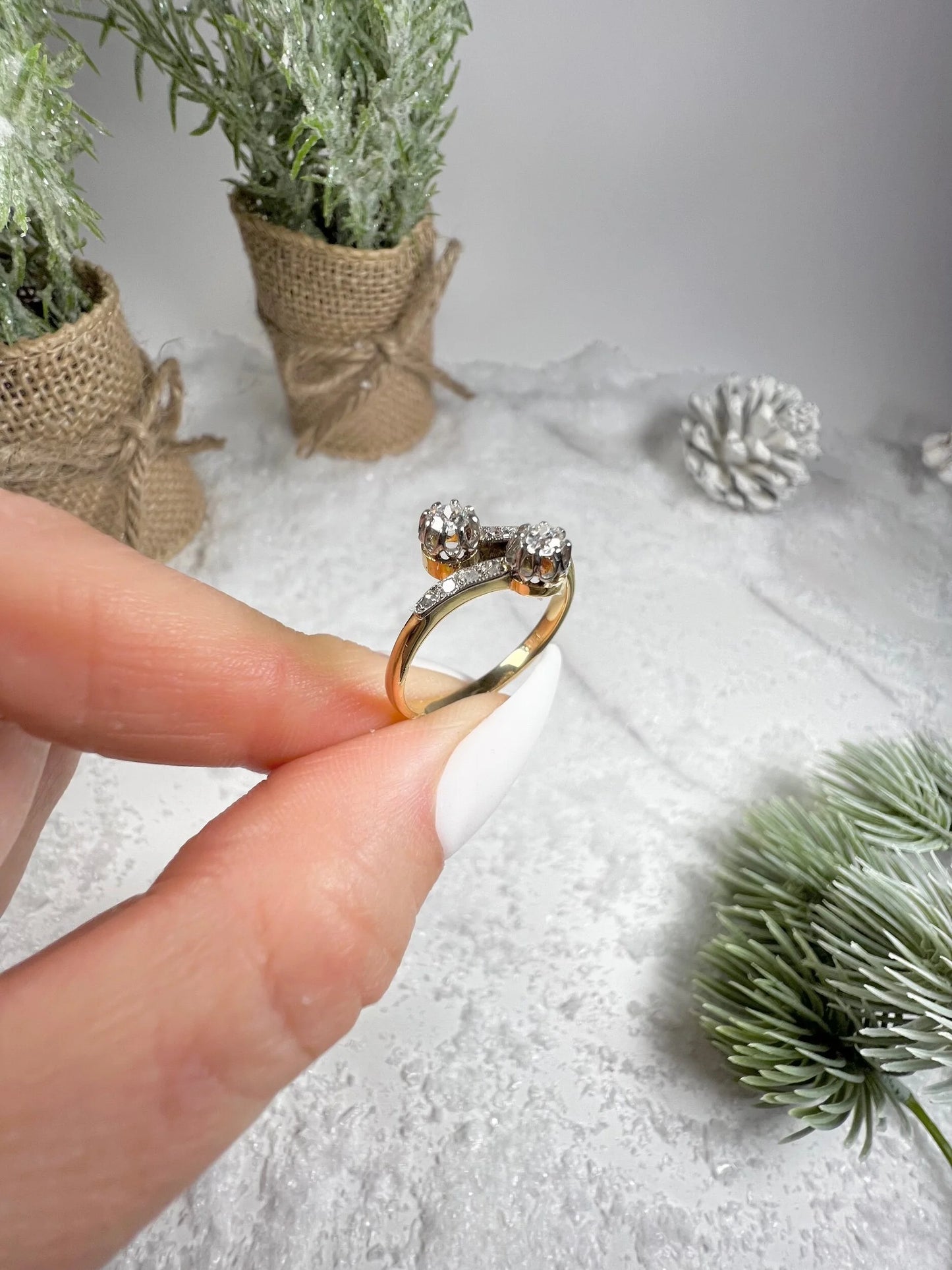 A two stone diamond crossover ring in yellow and white gold, held in a hand