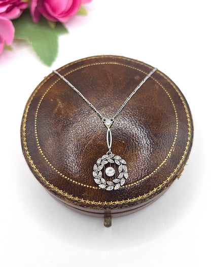A platinum floral wreath pendant with diamonds on a platinum chain