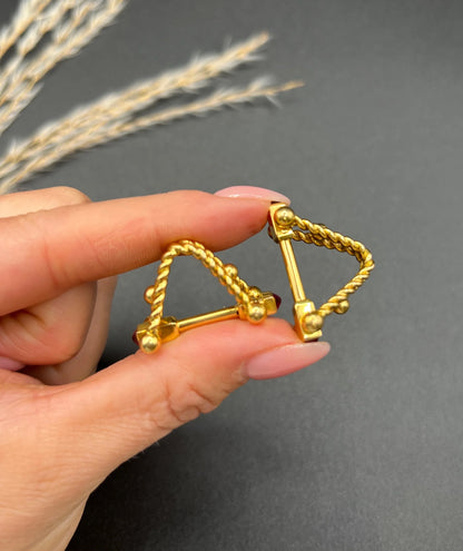 A pair of yellow gold ruby cufflinks, held in a hand