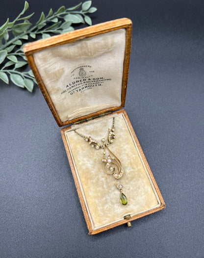 A yellow gold floral pendant necklace with pearls and a peridot drop, in an antique box