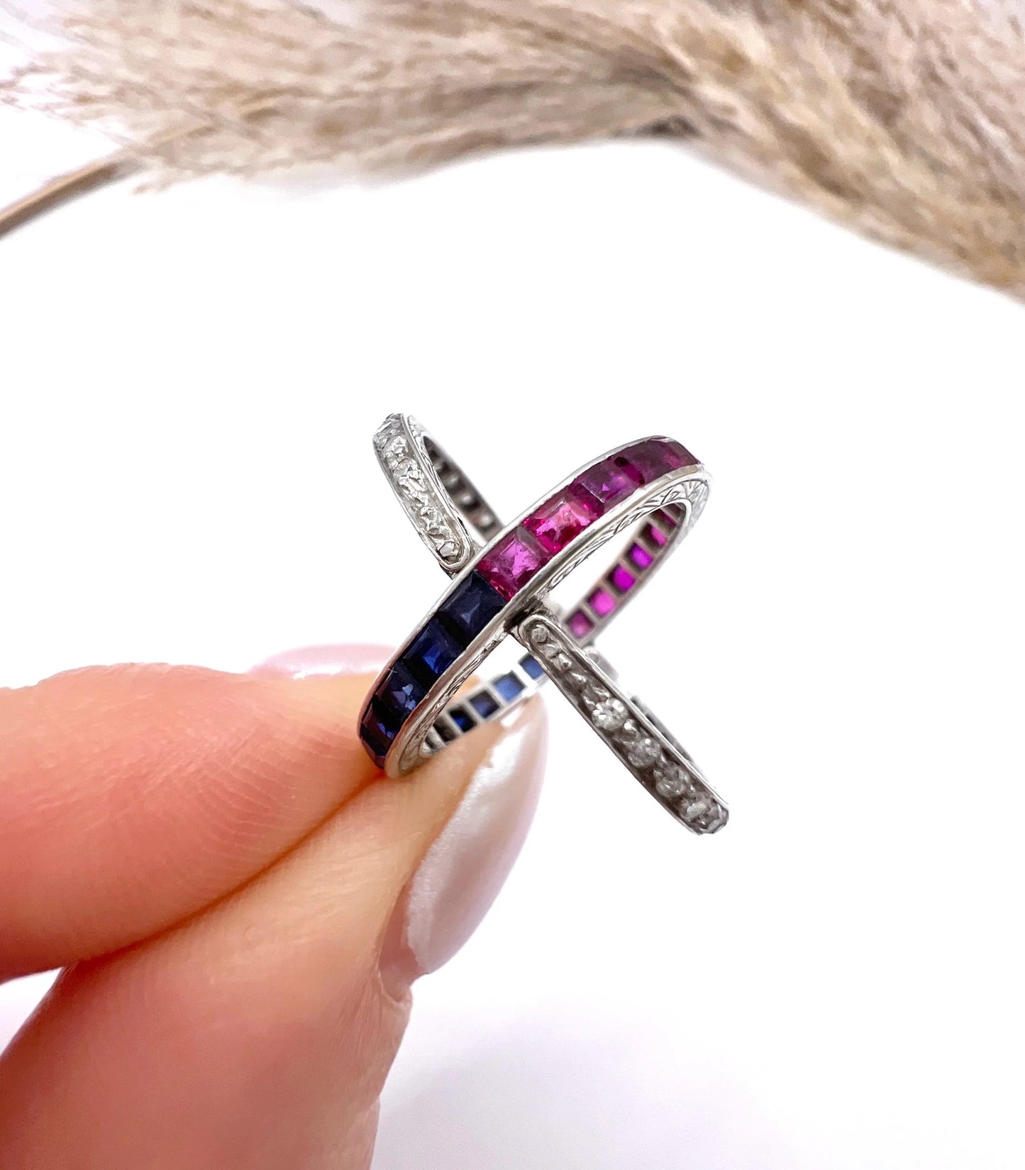 A platinum night and day flip band ring set with diamonds, sapphires and rubies, held in a hand