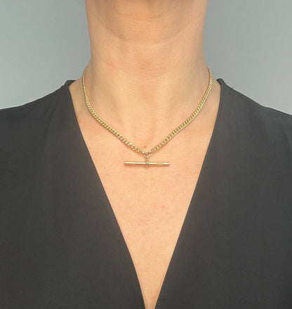 A yellow gold curb link Albert watch chain, modelled by a woman wearing a black top