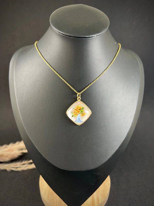 A vase of flowers reverse crystal pendant in yellow gold, with a chain, on a black bust
