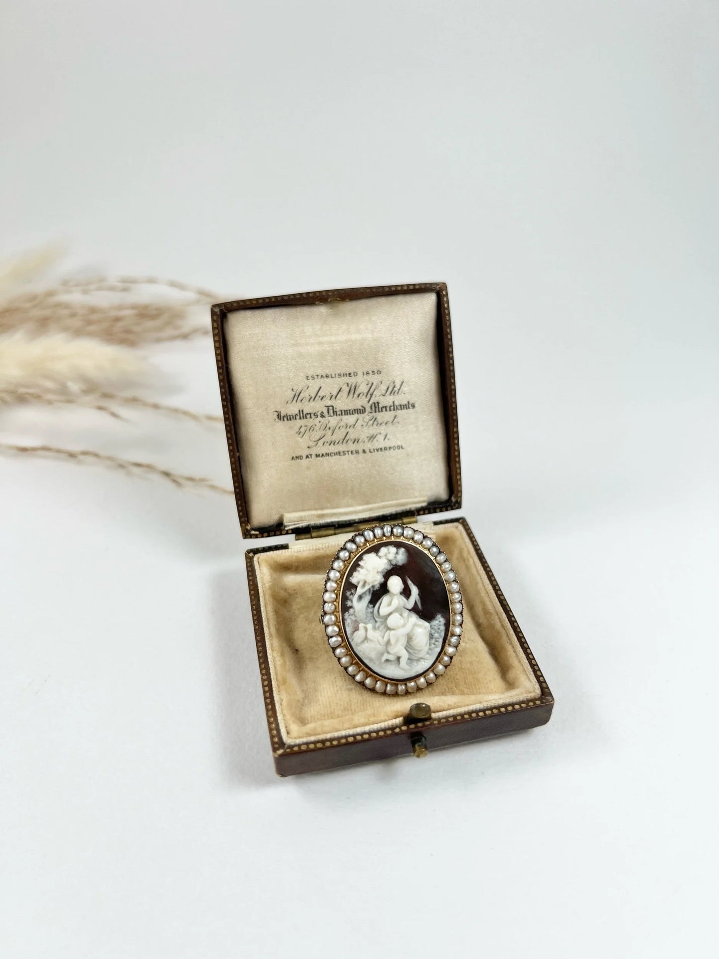 An antique oval cameo brooch depicting cherubs and birds, with a pearl border, set in gold