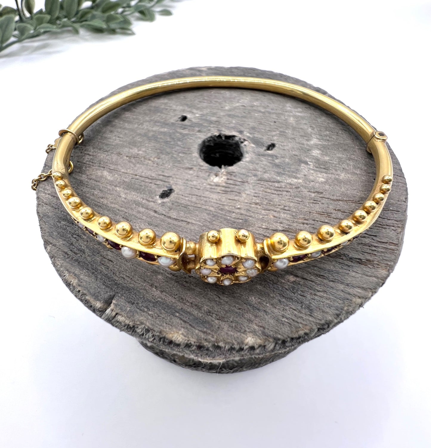 A yellow gold bangle bracelet set with rubies and seed pearls