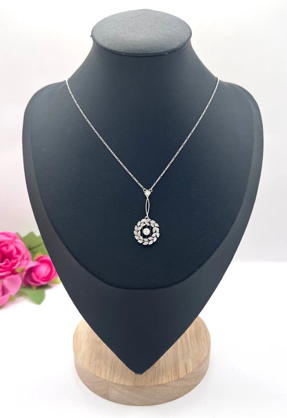 A platinum floral wreath pendant with diamonds on a platinum chain
