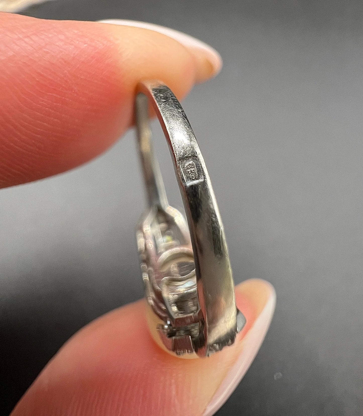 Close-up of a stamp on a white gold ring shank, held in a hand