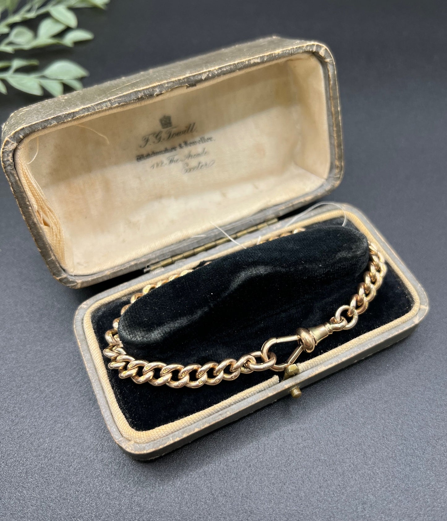 A gold curb link bracelet with a lobster claw clasp, in an antique bracelet box