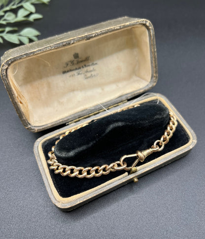 A gold curb link bracelet with a lobster claw clasp, in an antique bracelet box