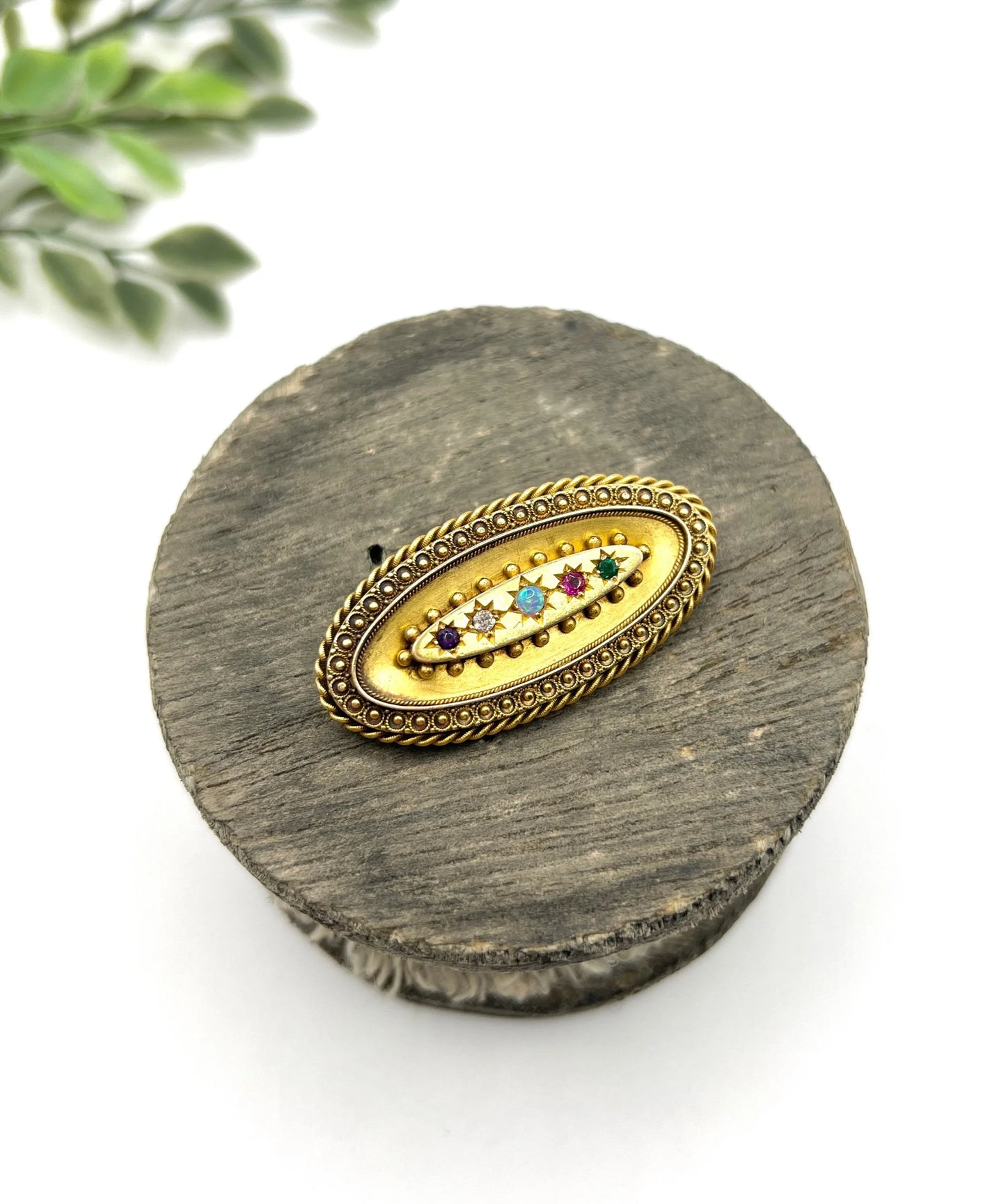 An oval yellow gold multi-gemstone acrostic brooch