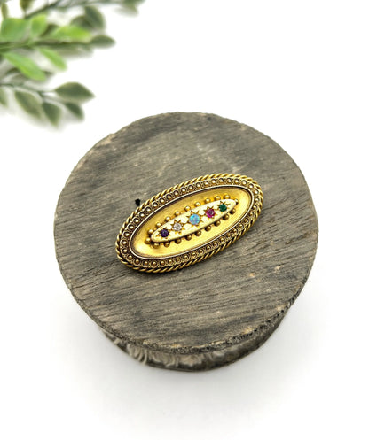 An oval yellow gold multi-gemstone acrostic brooch