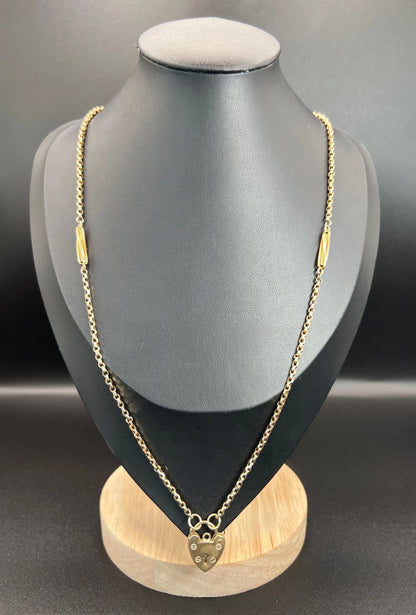 A yellow gold fancy link chain with a heart padlock, on a black bust