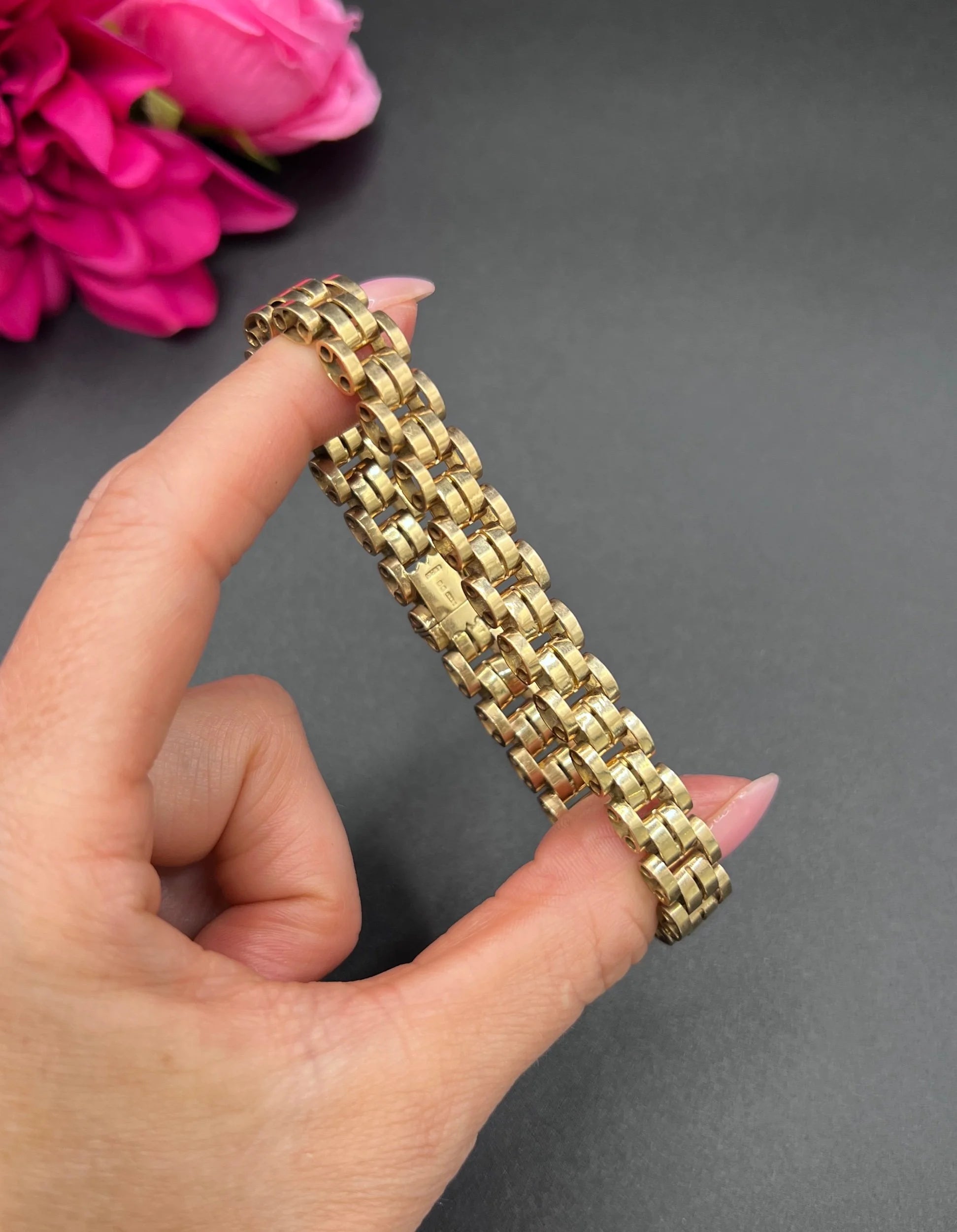 A yellow gold link bracelet, held in a hand