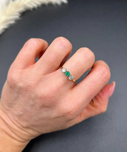 A three stone emerald and diamond ring in yellow gold and platinum, modelled on a hand