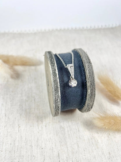 An old cut diamond pendant in white metal with a matching chain, on a circular object