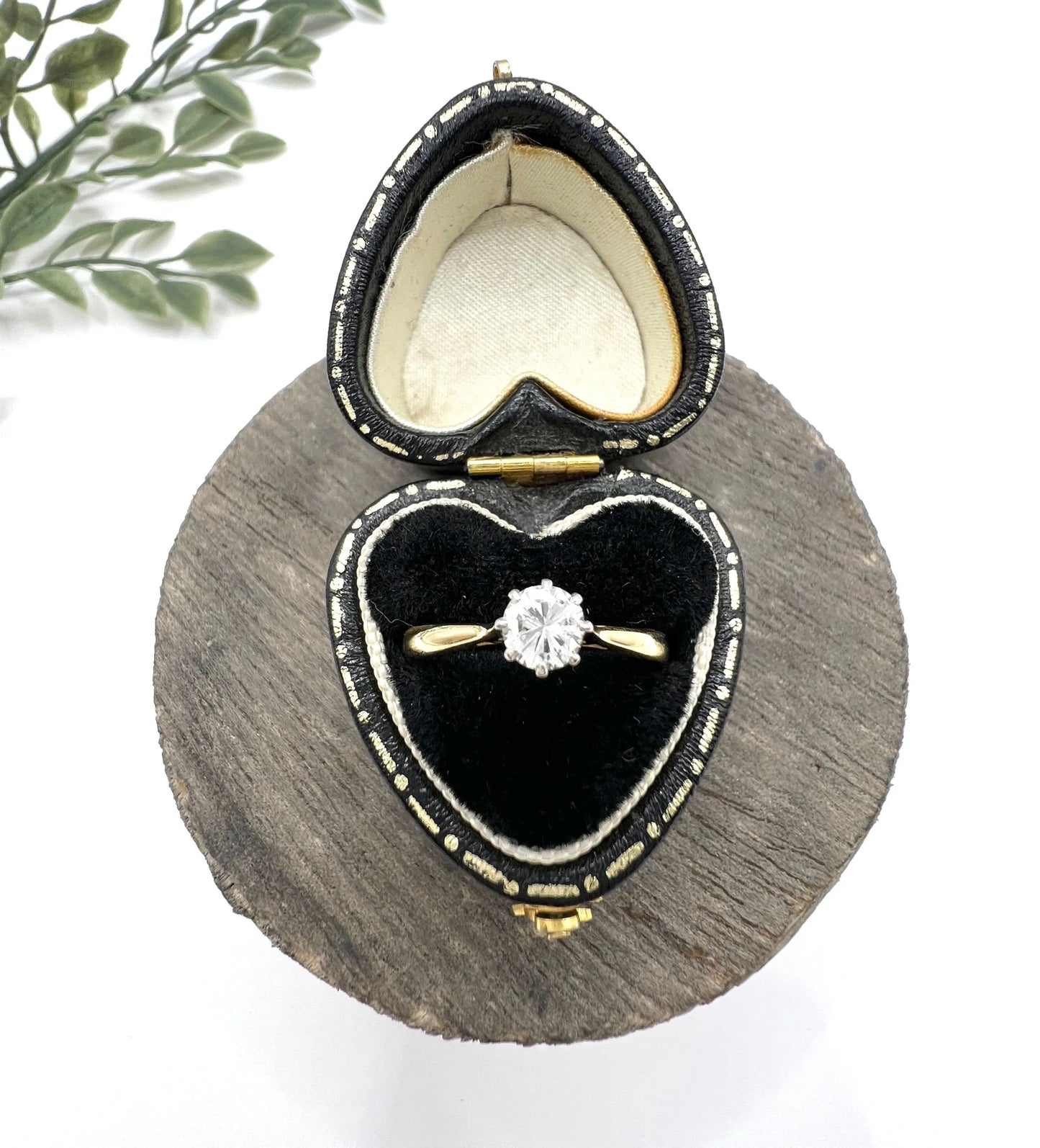 A single stone brilliant cut diamond ring claw set in platinum and yellow gold, in a heart-shaped ring box