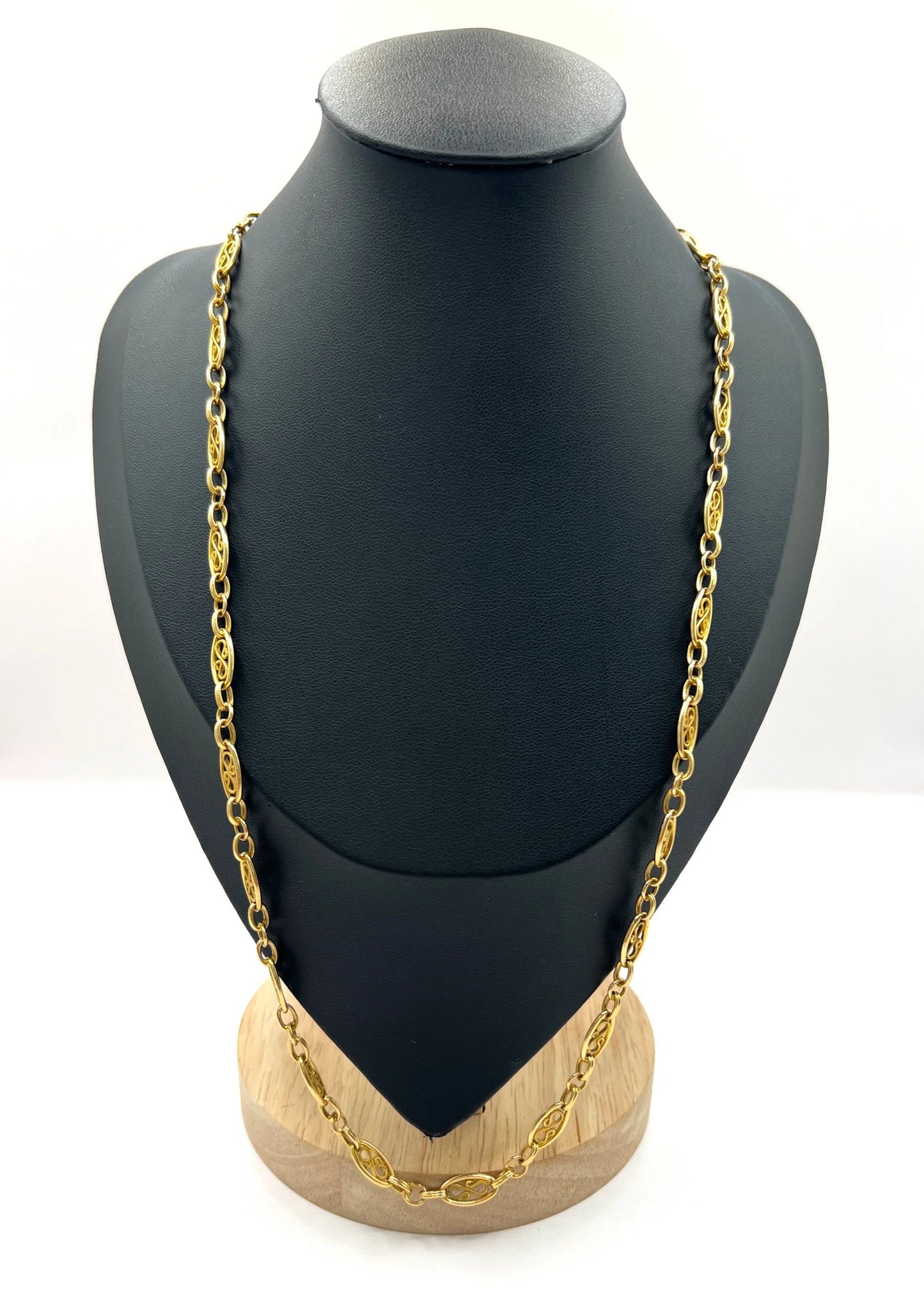 A yellow gold fancy link chain on a black jewellery bust