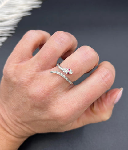 A white gold snake ring set with diamonds and with ruby eyes, modelled on a hand